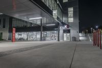 a parking garage with some red boxes on the concrete outside of it at night with lights shining