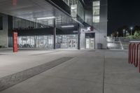 a parking garage with some red boxes on the concrete outside of it at night with lights shining