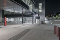 a parking garage with some red boxes on the concrete outside of it at night with lights shining