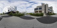 a 360 - zoom photograph of a skateboard park and a building on a cloudy day