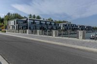 a large gray apartment complex sitting beside the water near a waterway with boats in it