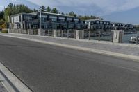 a large gray apartment complex sitting beside the water near a waterway with boats in it