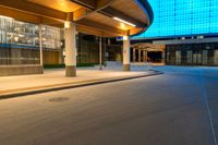 an empty road has a long walkway on it and buildings in the background with a light shine on