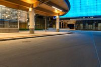 an empty road has a long walkway on it and buildings in the background with a light shine on