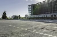 there is a parking lot in the middle of a large, open building with windows and many pine trees