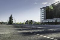 there is a parking lot in the middle of a large, open building with windows and many pine trees