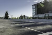 there is a parking lot in the middle of a large, open building with windows and many pine trees