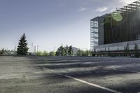 there is a parking lot in the middle of a large, open building with windows and many pine trees