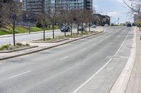 a road with a curb and parked cars on the side of it and buildings on the other side