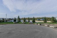 a large open parking lot with lots of buildings in the background and trees and grass