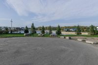 a large open parking lot with lots of buildings in the background and trees and grass