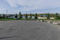 a large open parking lot with lots of buildings in the background and trees and grass