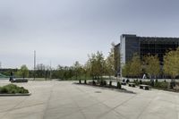 a concrete path and walkway in front of a building with many trees and bushes on the sides