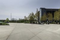 a concrete path and walkway in front of a building with many trees and bushes on the sides