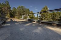 the concrete walkway that runs around an elevated metal structure in the woods is made out of silver steel bars