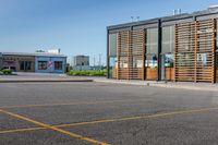 a parking lot in front of a glassed building with wooden slats on the outside