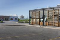 a parking lot in front of a glassed building with wooden slats on the outside