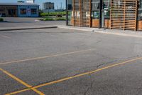 a parking lot in front of a glassed building with wooden slats on the outside