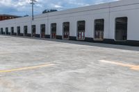 yellow arrows in an empty parking lot by an industrial building with large windows and signs