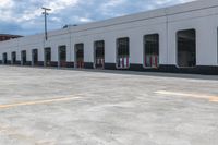 yellow arrows in an empty parking lot by an industrial building with large windows and signs