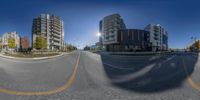 an empty street with three buildings in the background as seen through a fish eye lens