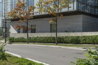 a motorcycle rider is riding on the street next to some trees and bushes with a glass building in the background