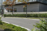 a motorcycle rider is riding on the street next to some trees and bushes with a glass building in the background