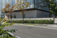 a motorcycle rider is riding on the street next to some trees and bushes with a glass building in the background