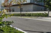 a motorcycle rider is riding on the street next to some trees and bushes with a glass building in the background