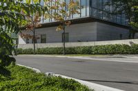 a motorcycle rider is riding on the street next to some trees and bushes with a glass building in the background