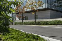 a motorcycle rider is riding on the street next to some trees and bushes with a glass building in the background