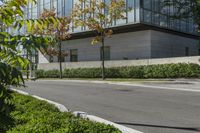 a motorcycle rider is riding on the street next to some trees and bushes with a glass building in the background