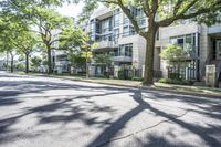 an empty street lined with trees next to a building in the middle of the day