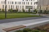 the bench is on the walkway in front of the building where there is a lawn and sidewalk