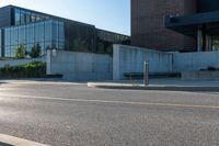 street with cement and glass building in background and bike parking area on street next to sidewalk