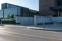 street with cement and glass building in background and bike parking area on street next to sidewalk