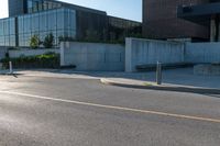 street with cement and glass building in background and bike parking area on street next to sidewalk