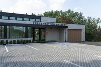 a modern building with a parking lot, driveway, and stone walkways for use in the presentation gallery