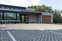 a modern building with a parking lot, driveway, and stone walkways for use in the presentation gallery