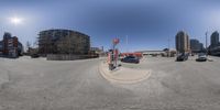 an intersection with several cars and buildings in the background - this is a 360 - lens photograph of a street