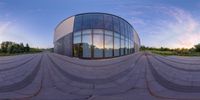 a 360 - zoom shot of a building with glass and concrete circular architecture and sunset