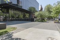 the sidewalk leading to an office building and sidewalk with bushes on either side and trees in the background