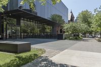 the sidewalk leading to an office building and sidewalk with bushes on either side and trees in the background