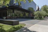 the sidewalk leading to an office building and sidewalk with bushes on either side and trees in the background