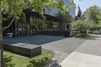 the sidewalk leading to an office building and sidewalk with bushes on either side and trees in the background