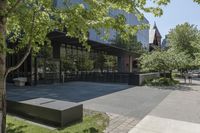 the sidewalk leading to an office building and sidewalk with bushes on either side and trees in the background