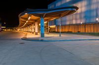 the empty sidewalk at a bus station in the city at night time with light on