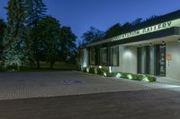 entrance and parking garage at night with lights illuminating on the building facade and trees in background