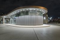 an empty parking lot at night with many windows at its side and lights on the windows