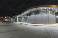 an empty parking lot at night with many windows at its side and lights on the windows